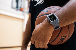 Guy stands on a basketball court wearing a Rhino Brand Apple Watch protector and black T-shirt. He's holding a basketball